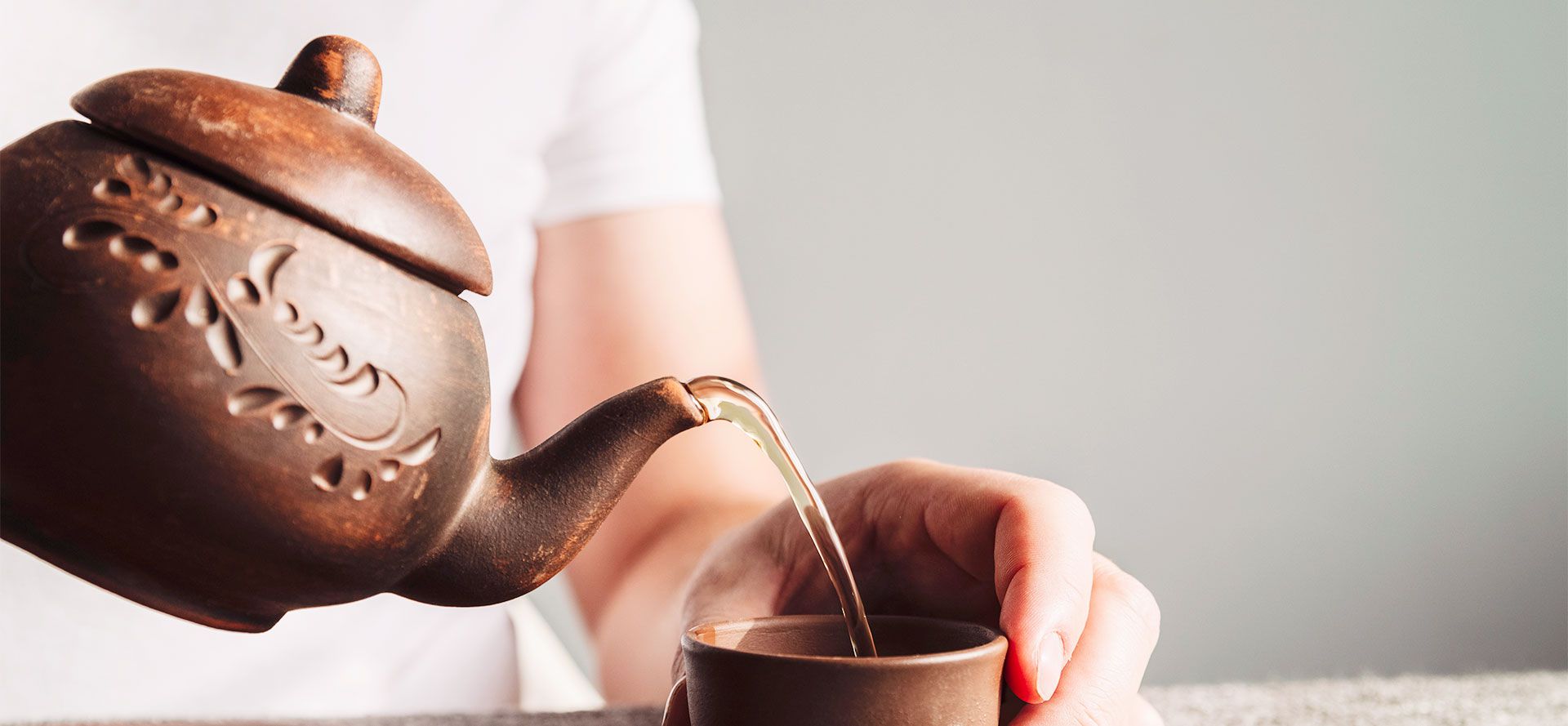 Pouring Tea From A Clay Teapot.